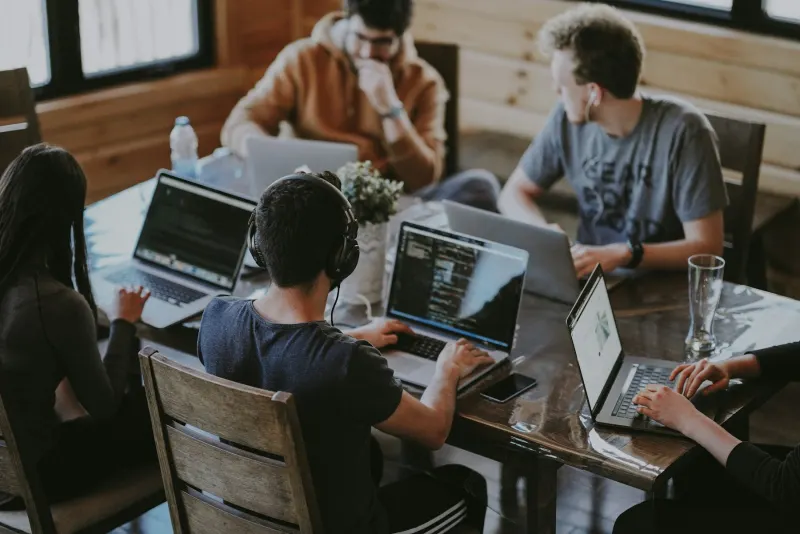 Team collaborating around a table with laptops in a bright workspace