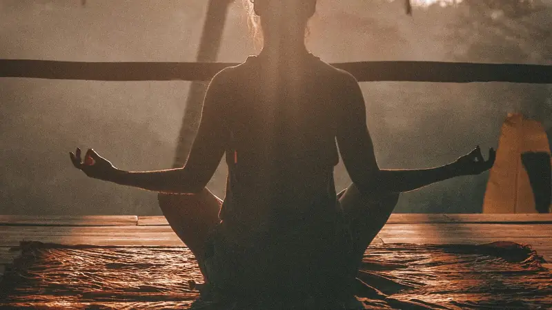Person sitting peacefully in a calm yoga pose on a mat