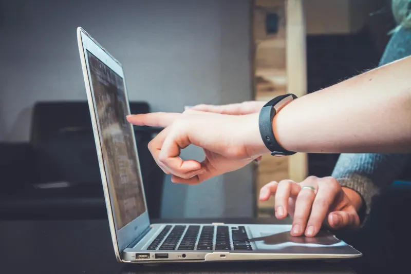 Person using a laptop for online learning at a wooden desk
